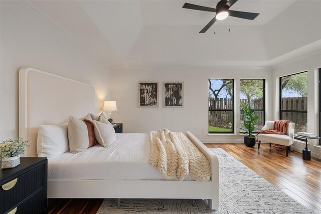 210 Hazeltine Dr, Lakeway, TX 78734 - bedroom featuring wood finished floors, a raised ceiling, crown molding, and ceiling fan