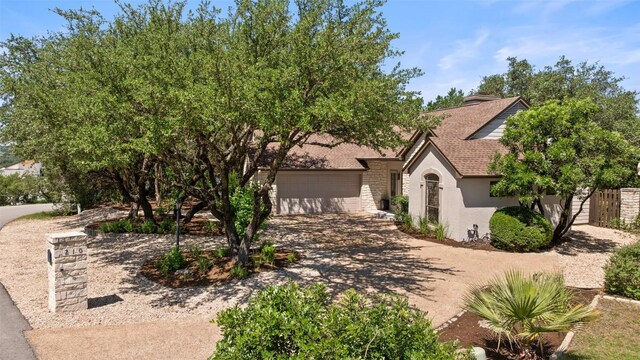 210 Hazeltine Dr, Lakeway, TX 78734 - view of front of home featuring stucco siding, an attached garage, roof with shingles, and driveway