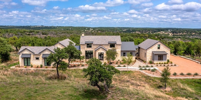 201 E Eldorado Ridge Dr, Fredericksburg, TX 78624 - view of front of house featuring stone siding, a standing seam roof, a chimney, and a forest view