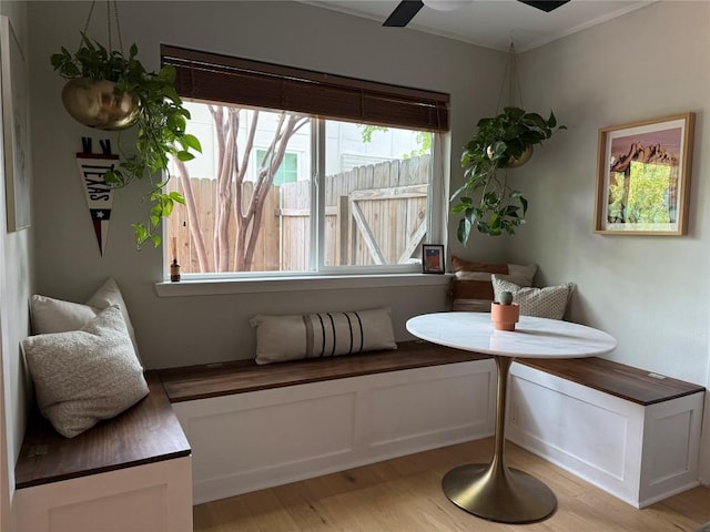 living area with light wood-type flooring, ornamental molding, and ceiling fan