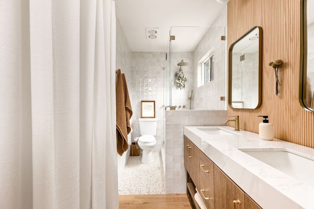 full bathroom with toilet, double vanity, and tile walls