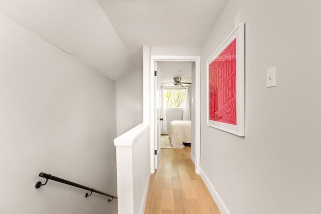 hall with light wood finished floors, an upstairs landing, and baseboards