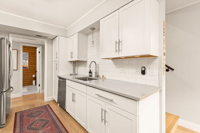 kitchen featuring a sink, stainless steel appliances, light wood-style flooring, and white cabinets