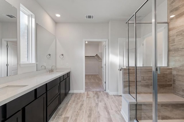 128 Green Knoll Ln, Georgetown, TX 78628 - bathroom featuring double vanity, a walk in closet, a shower stall, and recessed lighting