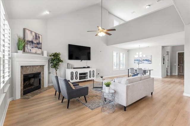 7207 Auburn Blaze Ln, Austin, TX 78744 - living room featuring a tile fireplace, light wood finished floors, ceiling fan, vaulted ceiling, and a chandelier