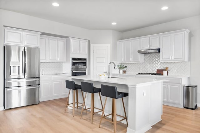 7207 Auburn Blaze Ln, Austin, TX 78744 - kitchen featuring stainless steel appliances, under cabinet range hood, tasteful backsplash, light countertops, and white cabinets