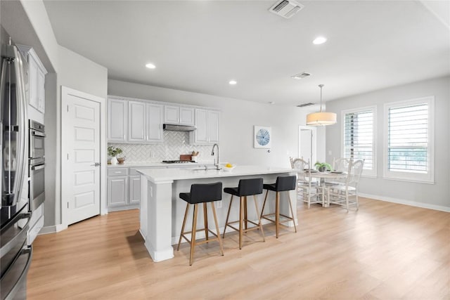 7207 Auburn Blaze Ln, Austin, TX 78744 - kitchen with light wood-type flooring, light countertops, a kitchen bar, backsplash, and recessed lighting