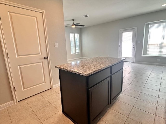 137 Rustic Glen Dr, San Marcos, TX 78666 - kitchen featuring light tile patterned floors, open floor plan, a ceiling fan, a kitchen island, and baseboards