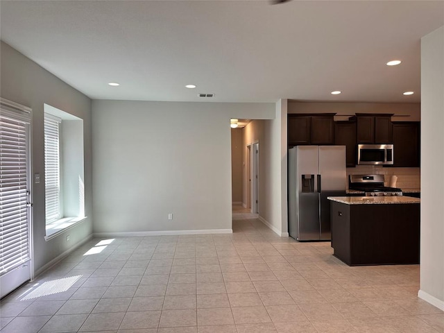 137 Rustic Glen Dr, San Marcos, TX 78666 - kitchen featuring appliances with stainless steel finishes, light stone counters, dark brown cabinetry, recessed lighting, and backsplash