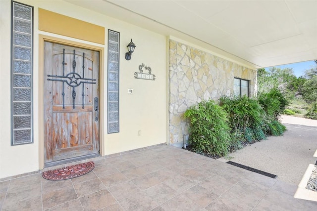 doorway to property featuring stone siding and a porch