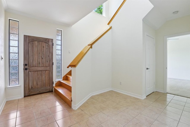 foyer entrance with light tile patterned floors, baseboards, and stairs
