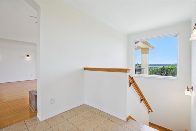 hallway with an upstairs landing, baseboards, and light tile patterned floors
