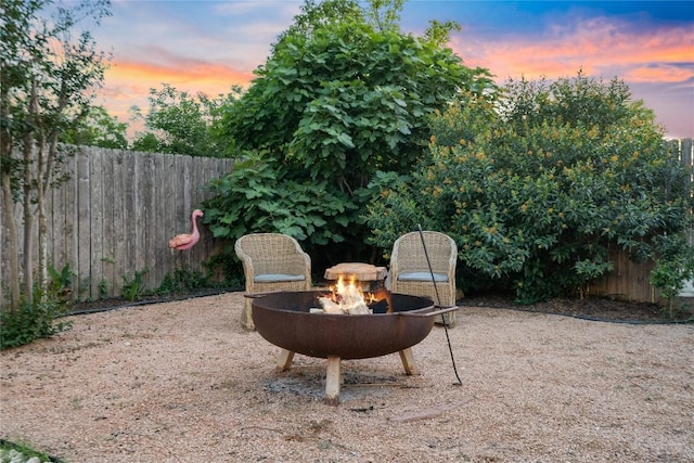 patio terrace at dusk with an outdoor fire pit and fence