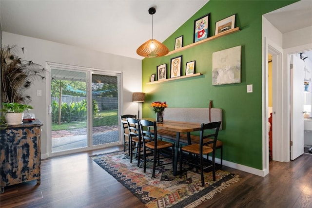 dining space featuring wood finished floors, vaulted ceiling, and baseboards