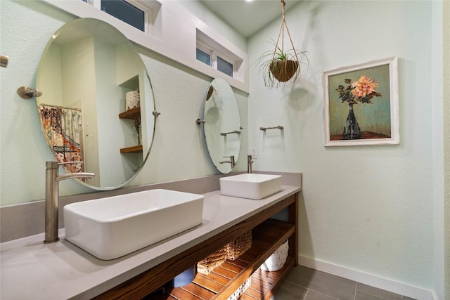 full bathroom featuring tile patterned flooring, double vanity, and baseboards