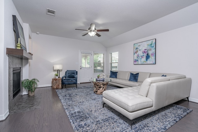 212 Beretta Cir, Georgetown, TX 78628 - living area with a ceiling fan, baseboards, a tile fireplace, dark wood finished floors, and vaulted ceiling