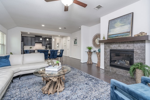 212 Beretta Cir, Georgetown, TX 78628 - living area featuring ceiling fan, dark wood finished floors, a tile fireplace, baseboards, and vaulted ceiling