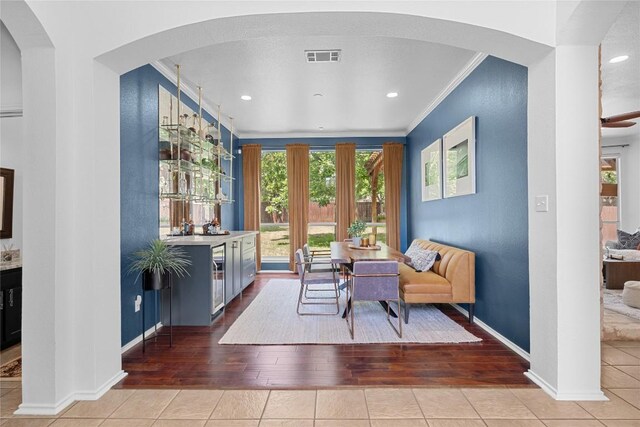 living area featuring crown molding, hardwood / wood-style floors, baseboards, arched walkways, and recessed lighting