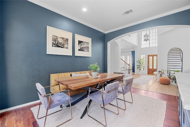 dining area with arched walkways, ornamental molding, stairway, wood finished floors, and baseboards