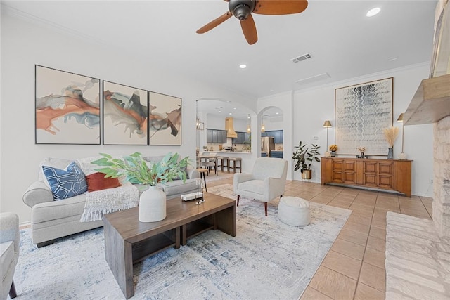 living room featuring arched walkways, ceiling fan, light tile patterned floors, crown molding, and recessed lighting