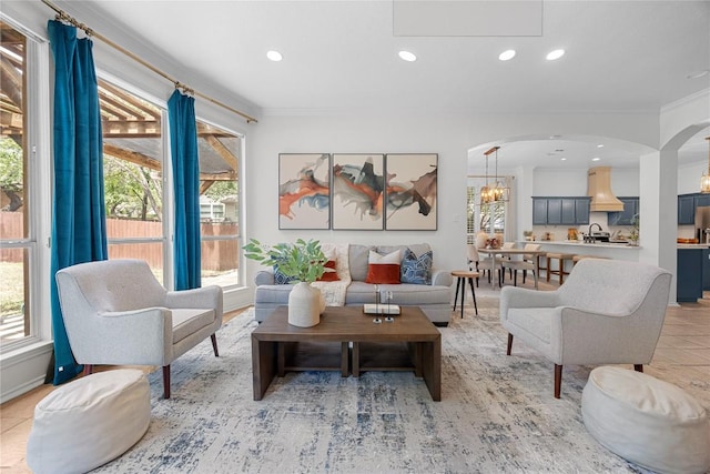 living area with arched walkways, recessed lighting, and crown molding