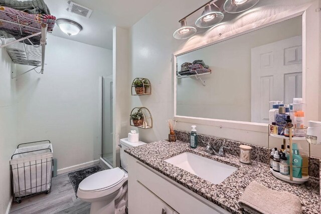 full bathroom featuring wood finished floors, a stall shower, toilet, and vanity