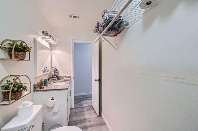 bathroom featuring toilet, wood finished floors, vanity, and baseboards