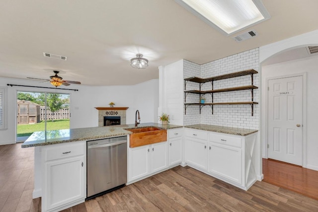 127 Edison Dr, Hutto, TX 78634 - kitchen featuring dishwasher, a sink, a peninsula, a fireplace, and light wood-style flooring