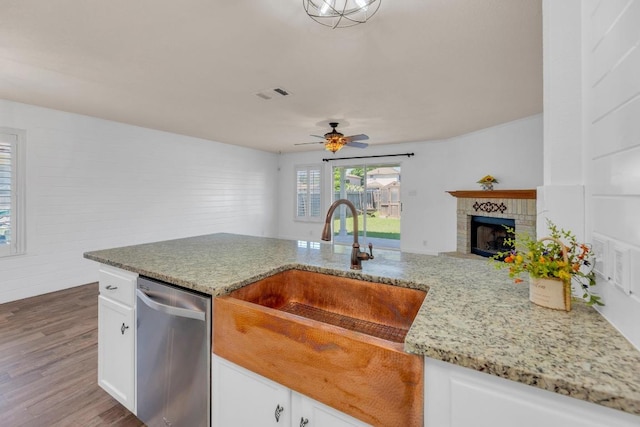 127 Edison Dr, Hutto, TX 78634 - kitchen with stainless steel dishwasher, a sink, light stone counters, and wood finished floors