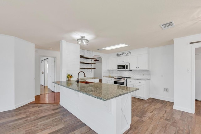 127 Edison Dr, Hutto, TX 78634 - kitchen featuring high end stove, open shelves, white cabinetry, a kitchen bar, and a peninsula