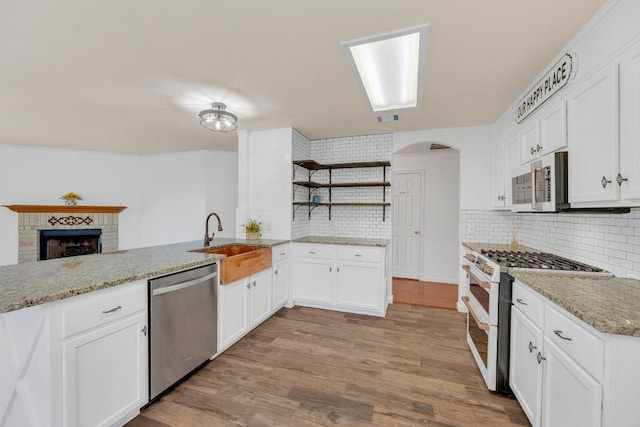 127 Edison Dr, Hutto, TX 78634 - kitchen featuring appliances with stainless steel finishes, open shelves, a sink, backsplash, and wood finished floors