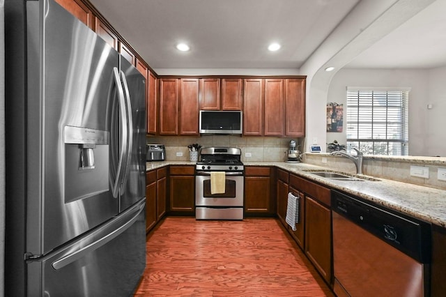 3101 Davis Ln Unit 6402, Austin, TX 78748 - kitchen featuring appliances with stainless steel finishes, a sink, wood finished floors, arched walkways, and light stone counters