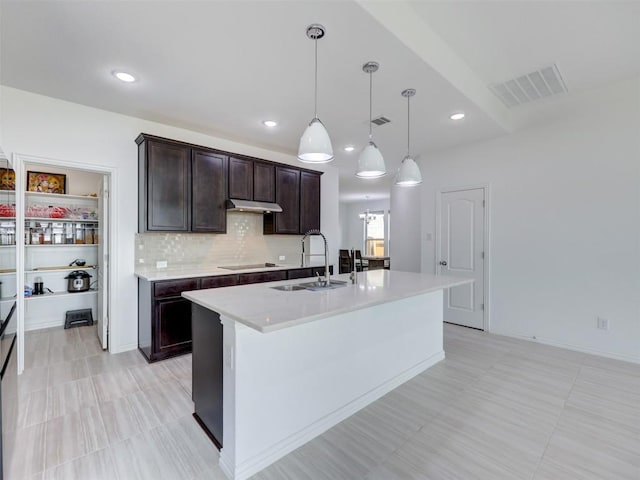 617 Silent Creek Cv, Georgetown, TX 78628 - kitchen featuring a sink, under cabinet range hood, light countertops, dark brown cabinetry, and a center island with sink