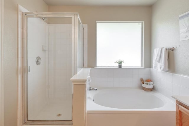 full bath with a stall shower, a garden tub, and vanity