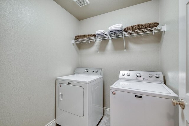 washroom with washing machine and clothes dryer and light tile patterned floors