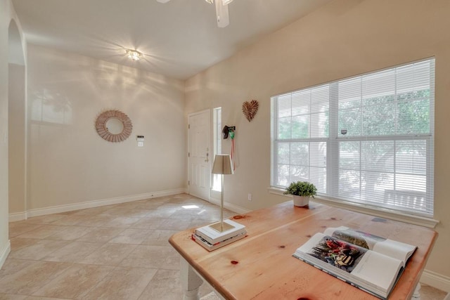 office featuring baseboards, arched walkways, ceiling fan, and light tile patterned floors