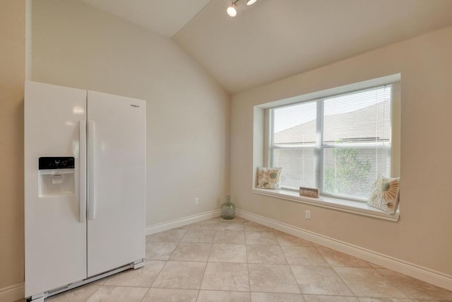 kitchen with white fridge with ice dispenser, vaulted ceiling, baseboards, and light tile patterned flooring