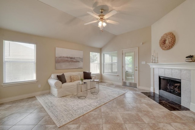 tiled living room with a tiled fireplace, a ceiling fan, vaulted ceiling, and baseboards