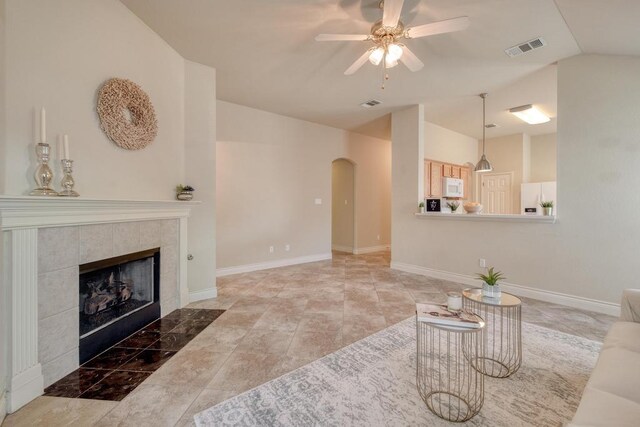 1303 Ridgewood Dr, Leander, TX 78641 - unfurnished living room featuring arched walkways, a ceiling fan, vaulted ceiling, a tile fireplace, and baseboards