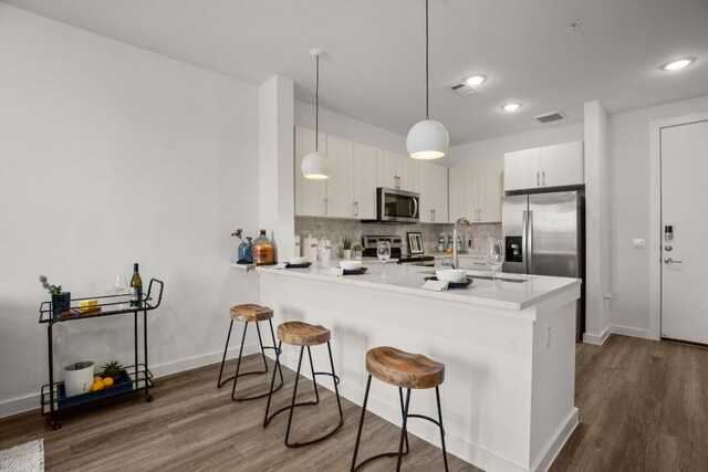 6324 N Lamar Blvd Unit 212, Austin, TX 78752 - kitchen featuring stainless steel appliances, a peninsula, a breakfast bar, dark wood-style flooring, and recessed lighting