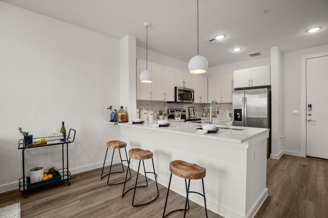 6324 N Lamar Blvd Unit 212, Austin, TX 78752 - kitchen with appliances with stainless steel finishes, a peninsula, a breakfast bar area, dark wood finished floors, and recessed lighting