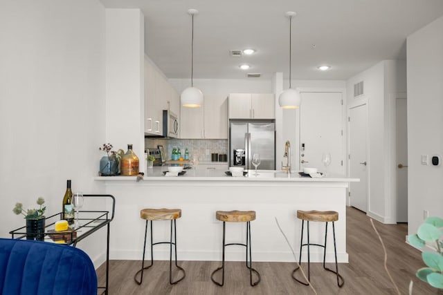 6324 N Lamar Blvd Unit 212, Austin, TX 78752 - kitchen featuring stainless steel appliances, a breakfast bar area, a peninsula, decorative light fixtures, and light countertops
