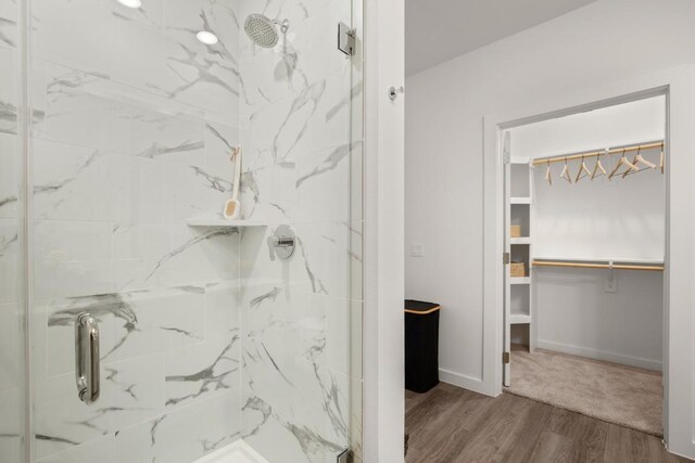 6324 N Lamar Blvd Unit 212, Austin, TX 78752 - bathroom featuring a marble finish shower, a spacious closet, wood finished floors, and baseboards