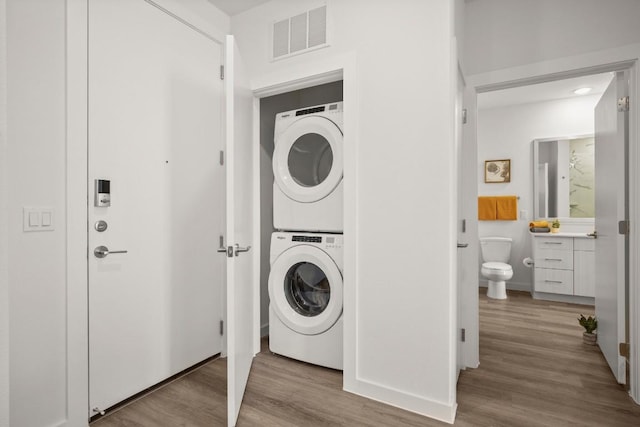 6324 N Lamar Blvd Unit 212, Austin, TX 78752 - laundry room with stacked washer and clothes dryer, wood finished floors, and baseboards