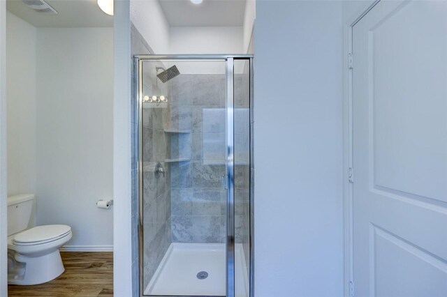 full bathroom with a shower stall, toilet, baseboards, and wood finished floors