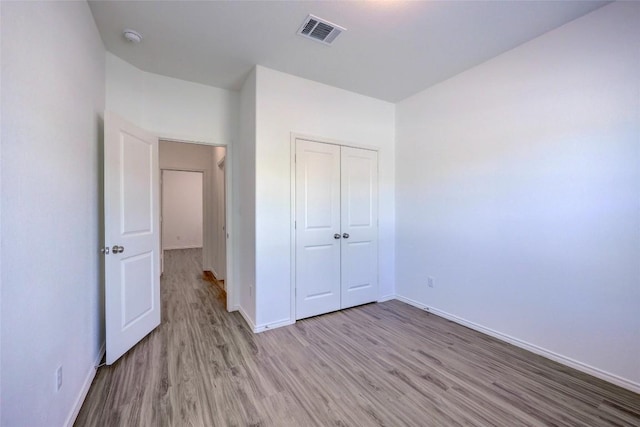 unfurnished bedroom with light wood finished floors, baseboards, and a closet