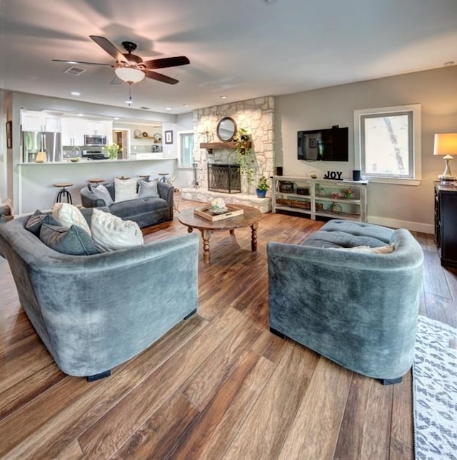 11408 Spicewood Pkwy, Austin, TX 78750 - living area with wood finished floors, a ceiling fan, and a stone fireplace