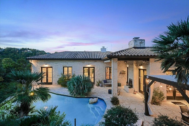 698 Windsong Trl, West Lake Hills, TX 78746 - back of property with a tile roof, a chimney, french doors, a patio area, and stone siding