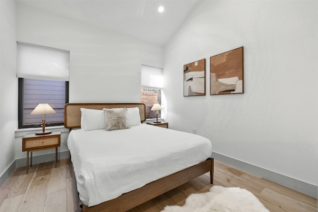 bedroom featuring baseboards, wood finished floors, and lofted ceiling