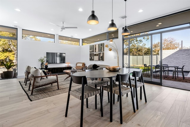 dining space featuring light wood-style floors, ceiling fan, recessed lighting, and a wall of windows